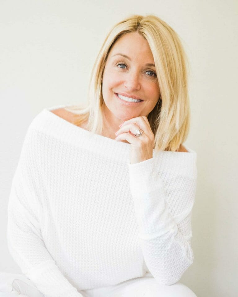 Menopause health podcaster Deanna wearing a white sweater and smiling